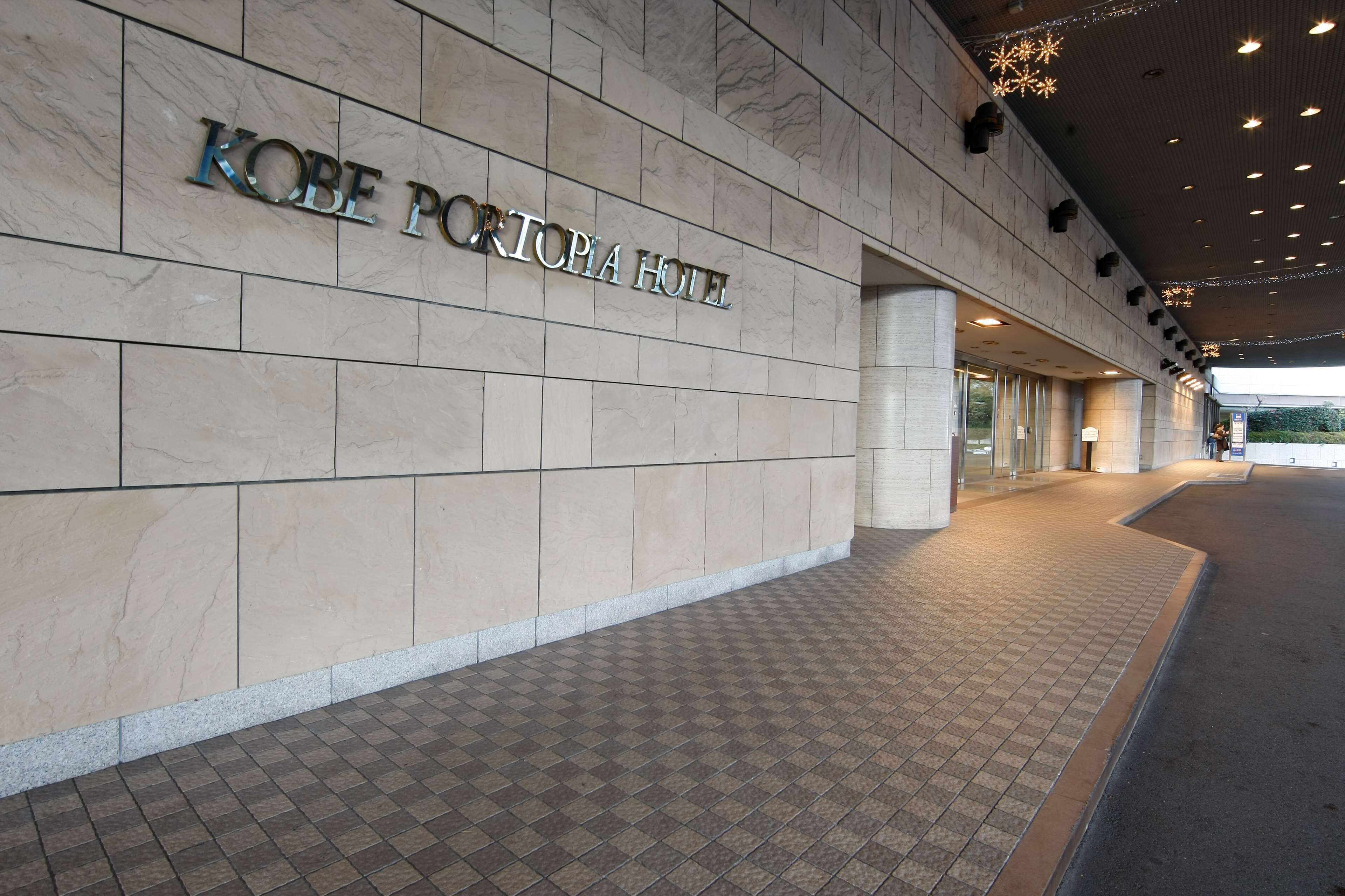 Een hotel ingang met een betegelde vloer en een bord waarop 'KOBE PORTOPIA HOTEL' staat.