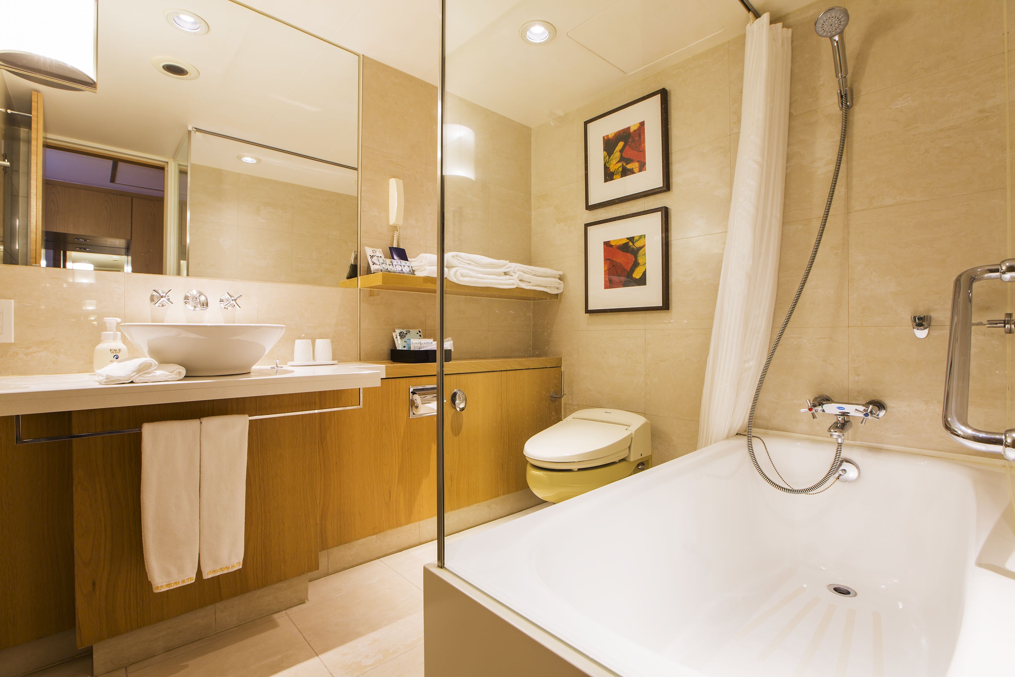 A modern bathroom with a large bathtub, a sink, and a toilet. There are two framed pictures on the wall.