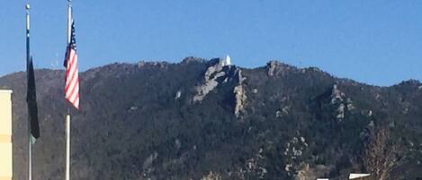 A mountain with a flagpole in the foreground.