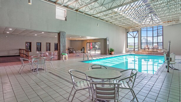 Une piscine intérieure avec un sol carrelé, des chaises et des tables en métal.