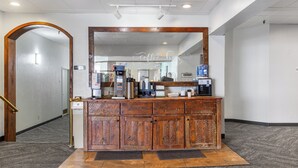 Un espace d’accueil avec un comptoir en bois, une machine à café et un panneau indiquant « Café ».