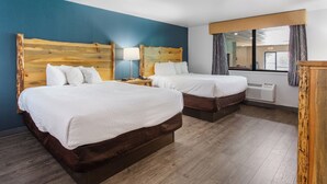 Une chambre d’hôtel avec deux lits, une tête de lit en bois, une table de chevet avec une lampe, une fenêtre avec des rideaux et un appareil de climatisation.