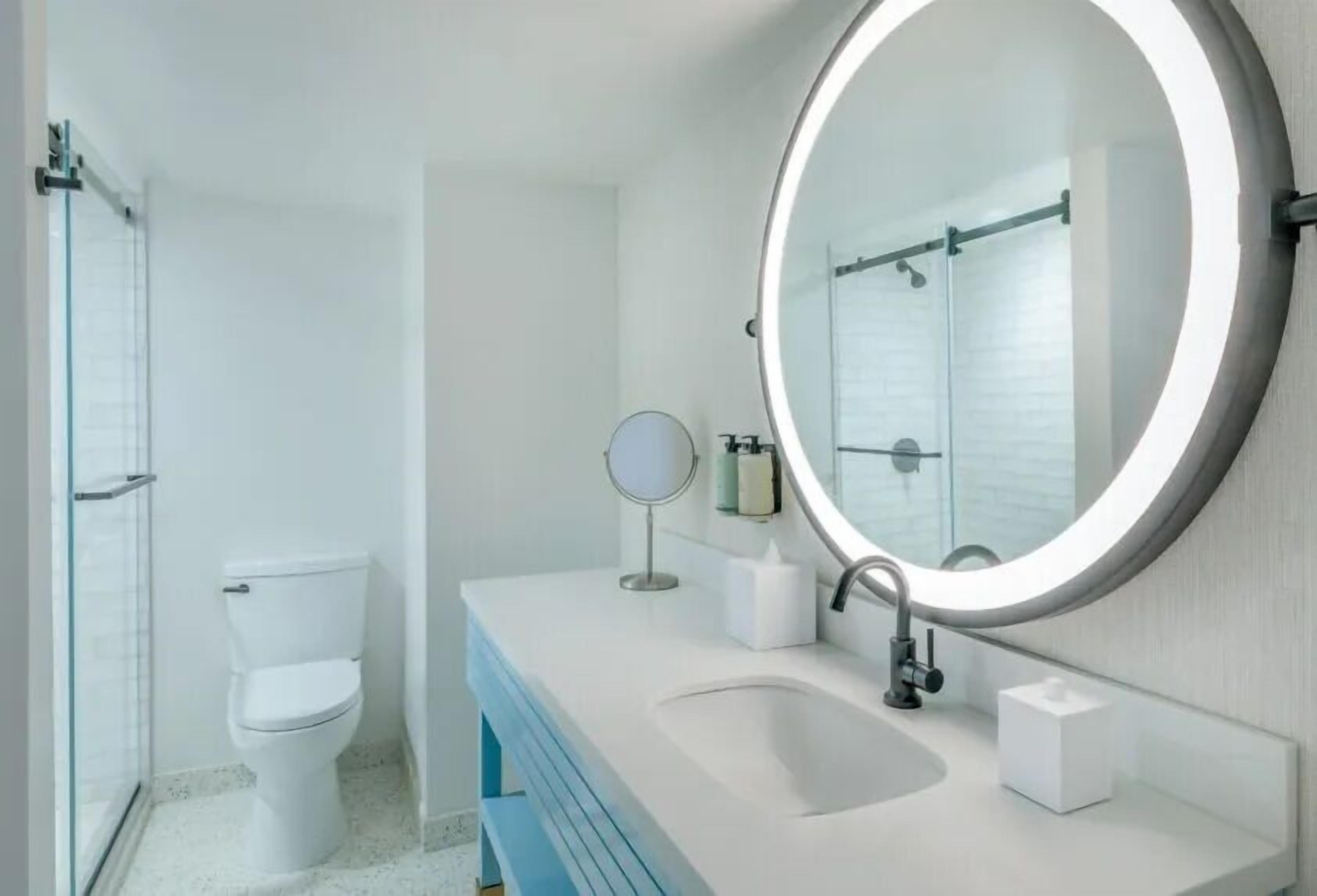 Un baño con inodoro, lavabo con espejo y zona de ducha.