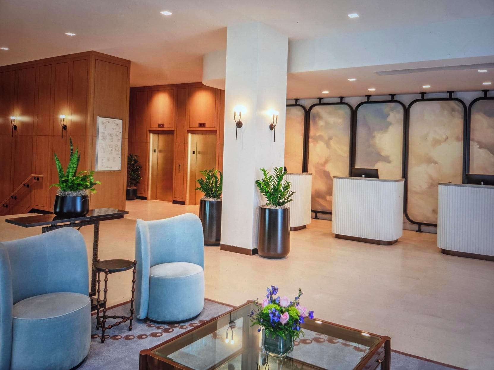 A hotel lobby with seating, reception desk, and elevators.