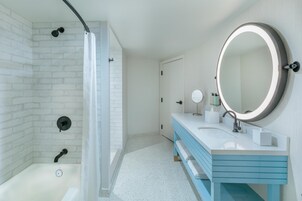 Un baño con ducha, lavamanos con espejo y una puerta.