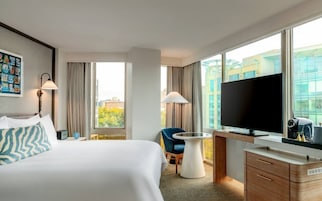 Une chambre d’hôtel équipée d’un lit, d’un bureau, d’une chaise, d’une télévision et d’une fenêtre donnant sur la ville.