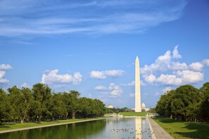 The Washington Monument with a clear sky, reflecting pool, and surrounding trees. - The Beacon at Embassy Row (Washington)