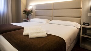 A hotel room with two beds, a bedside table with a lamp, and a nightstand with a phone. - B&B Hotel Zaragoza Royal (Zaragoza)