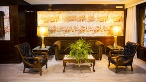 A room with a large painting on the wall, two armchairs, a coffee table with a plant, and two lamps. - B&B Hotel Zaragoza Royal (Zaragoza)