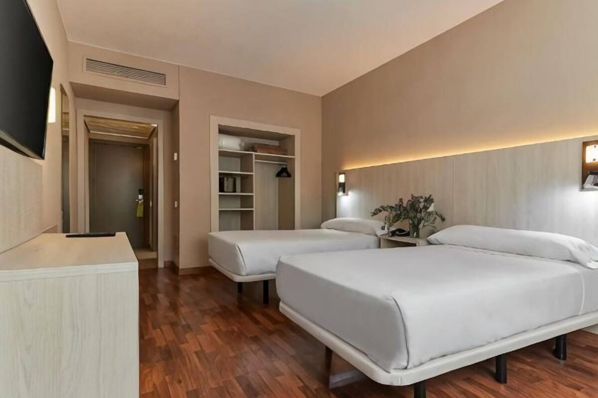 Een hotelkamer met twee bedden, een bureau, een kledingkast en een televisie.