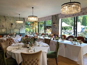 Un restaurante con mesas redondas, candelabros y centros de mesa florales.