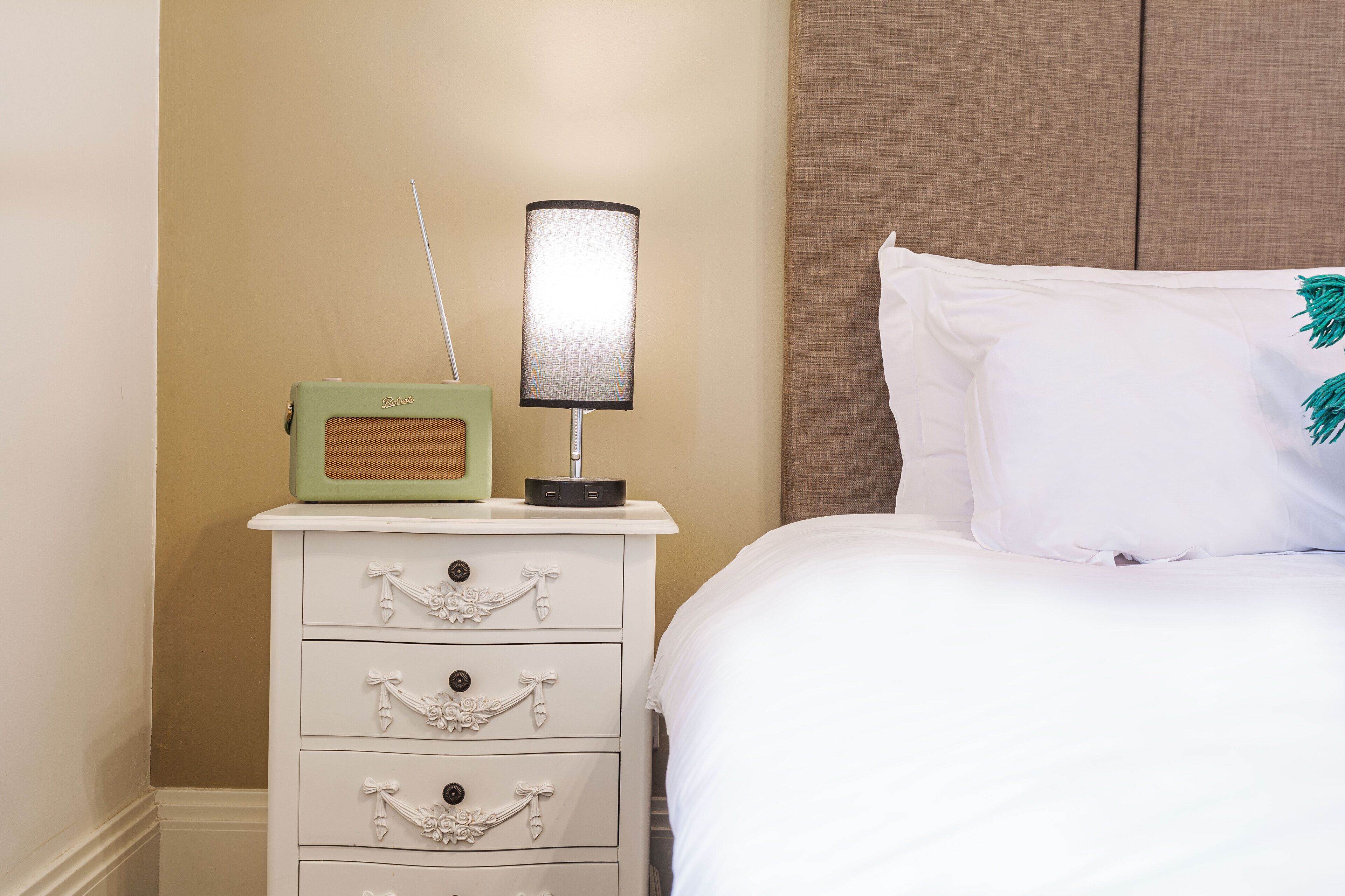 A neatly made bed with white bedding and a decorative pillow.