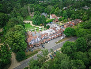 An aerial view of a large, historic building with multiple wings, surrounded by lush greenery and a parking area. - Forest Park Country Hotel & Inn, Brockenhurst, New Forest (Brockenhurst)