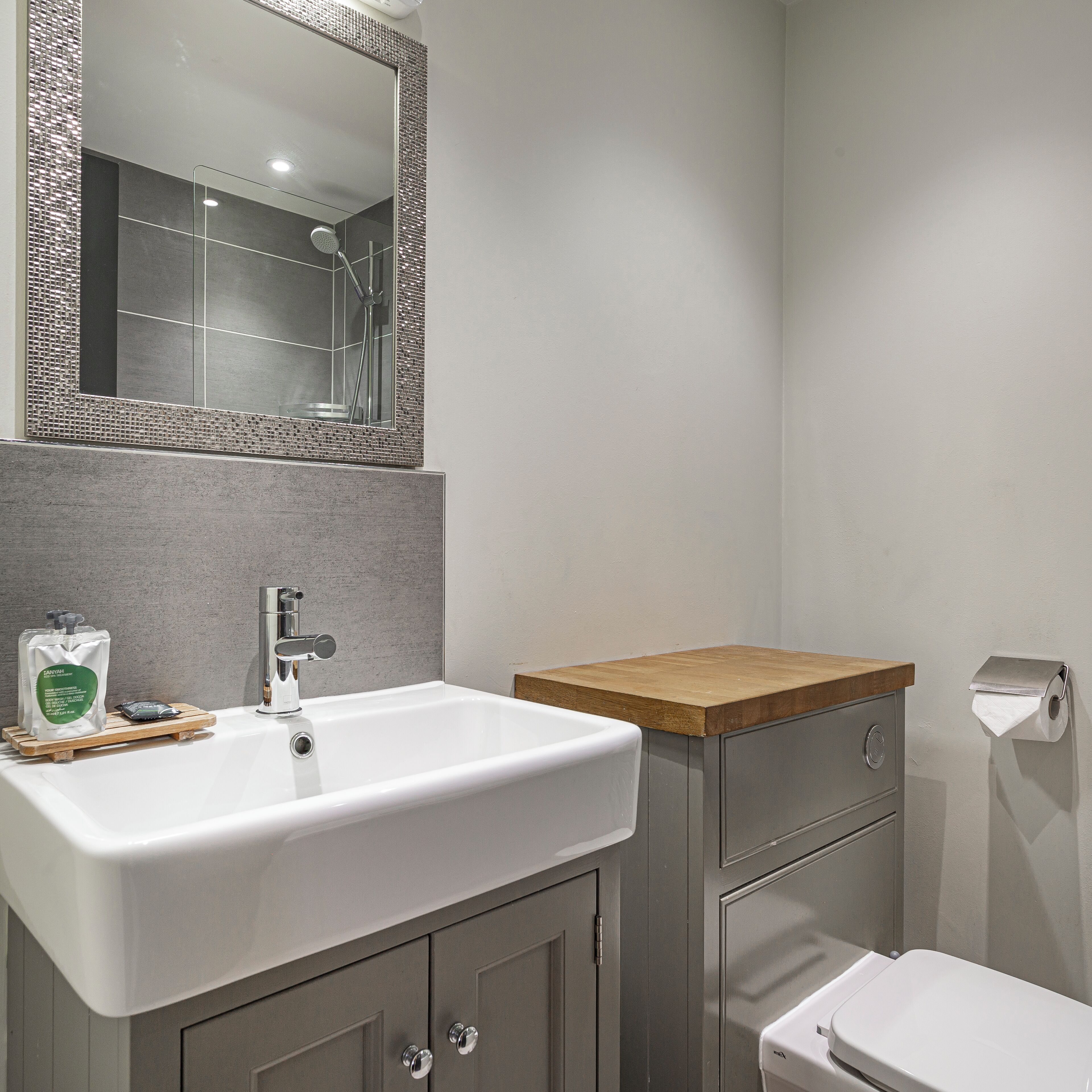 A bathroom with a white sink, a mirror, a shower, and a toilet.