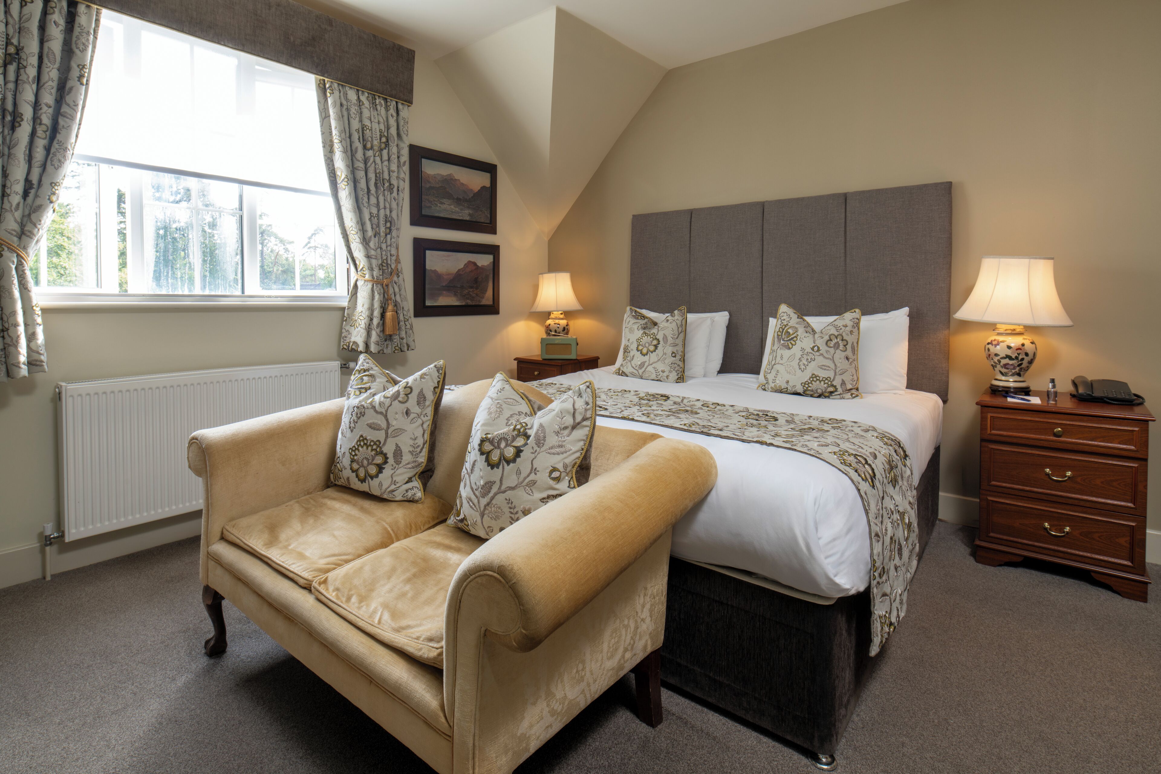 A bedroom with a bed, a sofa, a nightstand, and a lamp.