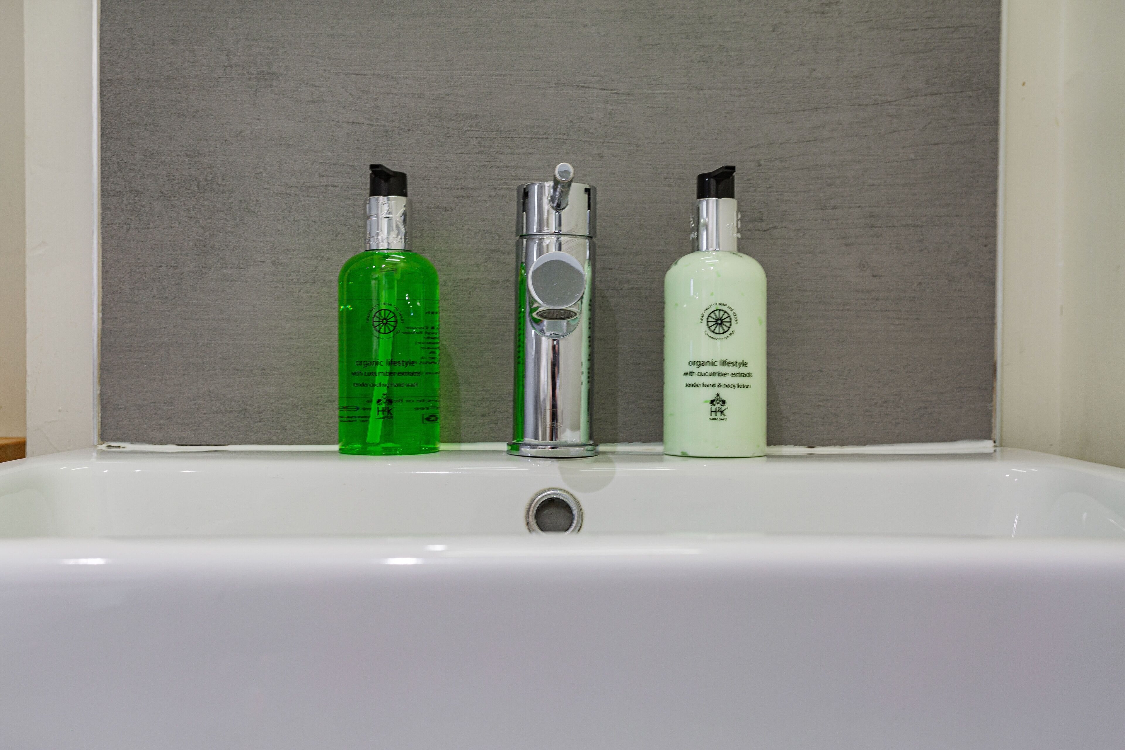 A bathroom sink with three bottles of personal care products.