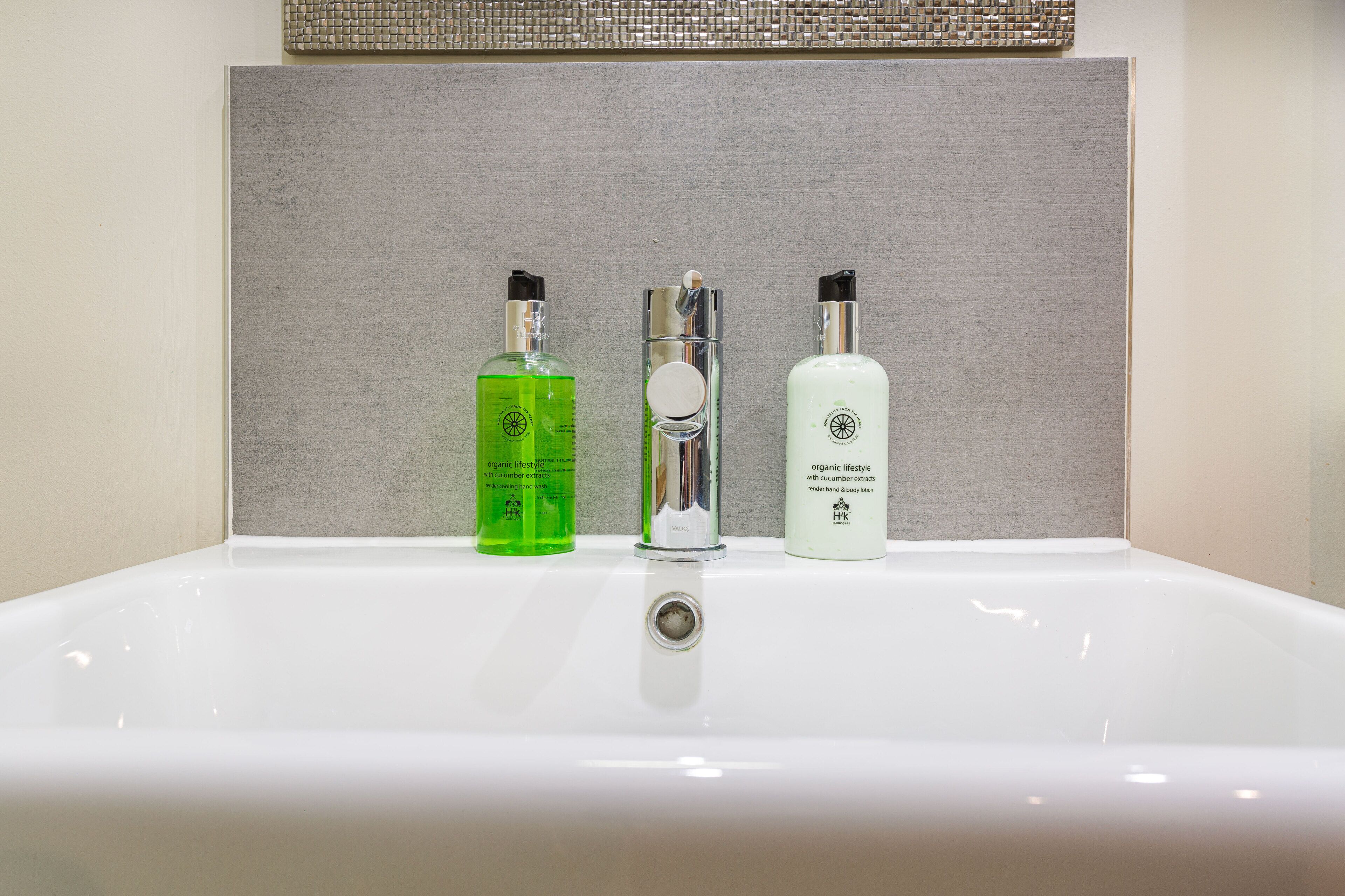A bathroom sink with three bottles of organic lifestyle products.