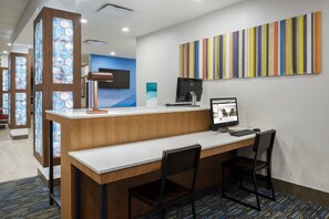 Una reception hotel con un computer, due sedie e un'opera d'arte con motivi a strisce colorate.