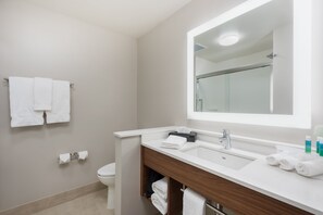 Un bagno moderno con un lavandino, uno specchio e un portasciugamani bianchi.