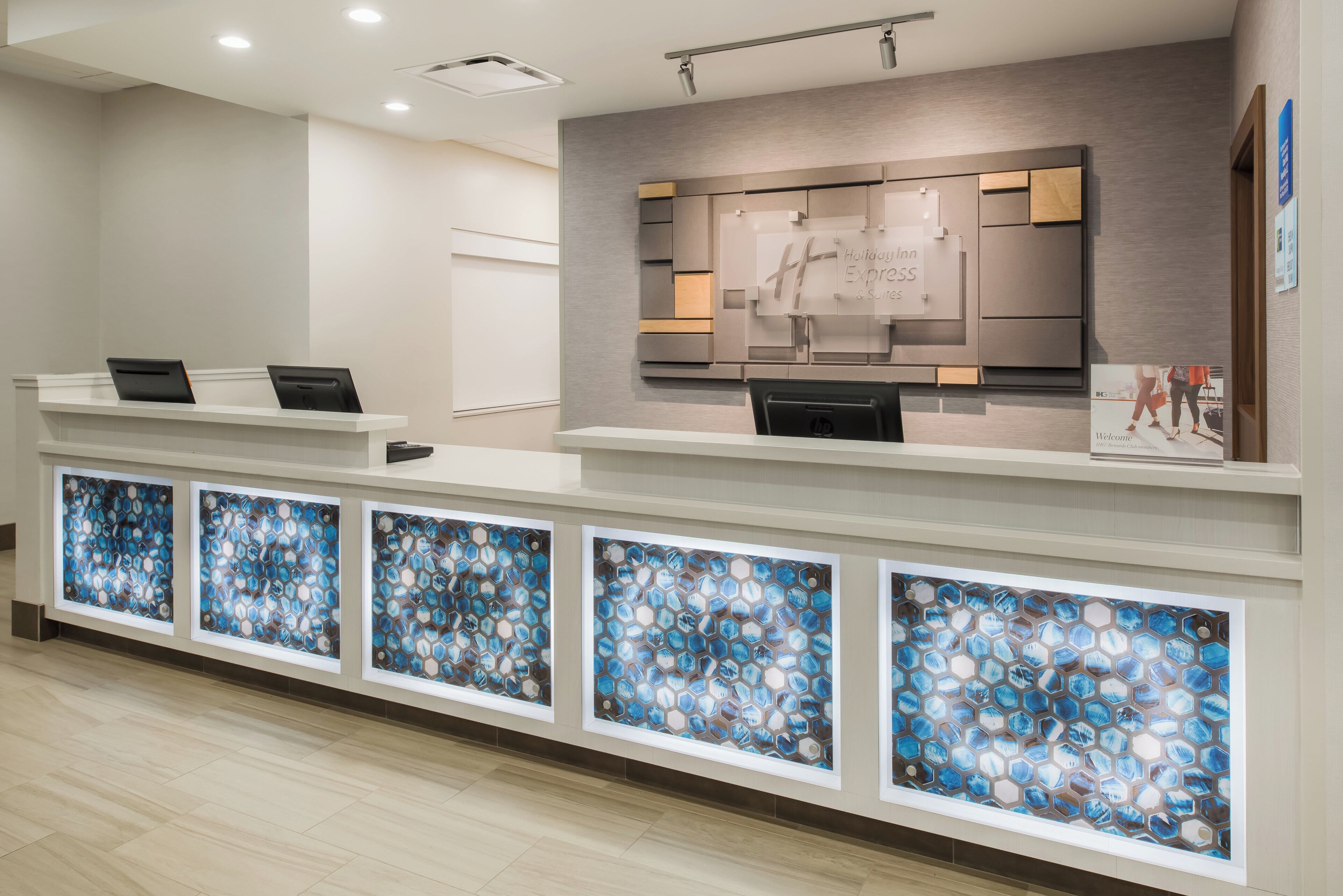 A hotel reception desk with a modern design, a digital display, and a series of glass panels.