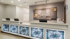A hotel reception desk with a modern design, a digital display, and a series of glass panels.