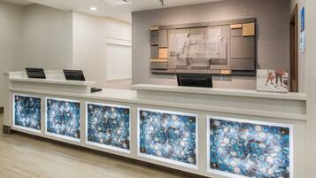 A hotel reception desk with a modern design, a digital display, and a series of glass panels.