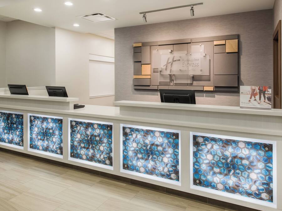 A hotel reception desk with a modern design, a digital display, and a series of glass panels.