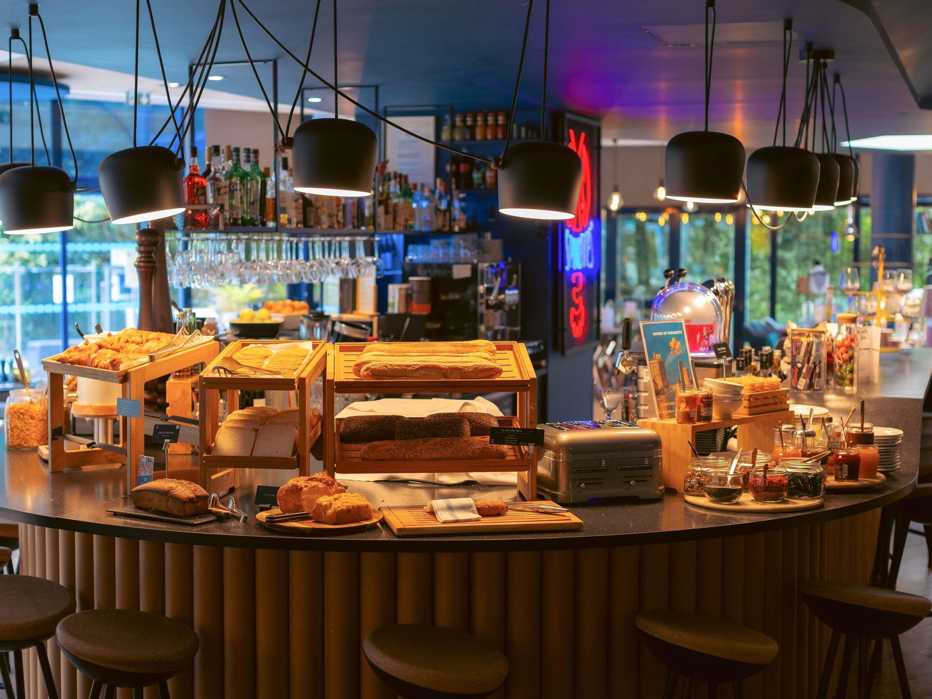 A breakfast bar with various pastries and bread, a coffee machine, and bar tools.