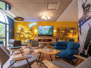 Relax in a warm and inviting lounge area with a large flat-screen TV, comfortable seating, and a fireplace.