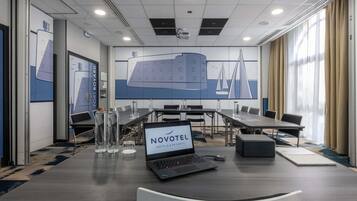 A conference room with a laptop, water bottles, and a sign reading 'NOVOTEL HOTELS & RESORTS'.