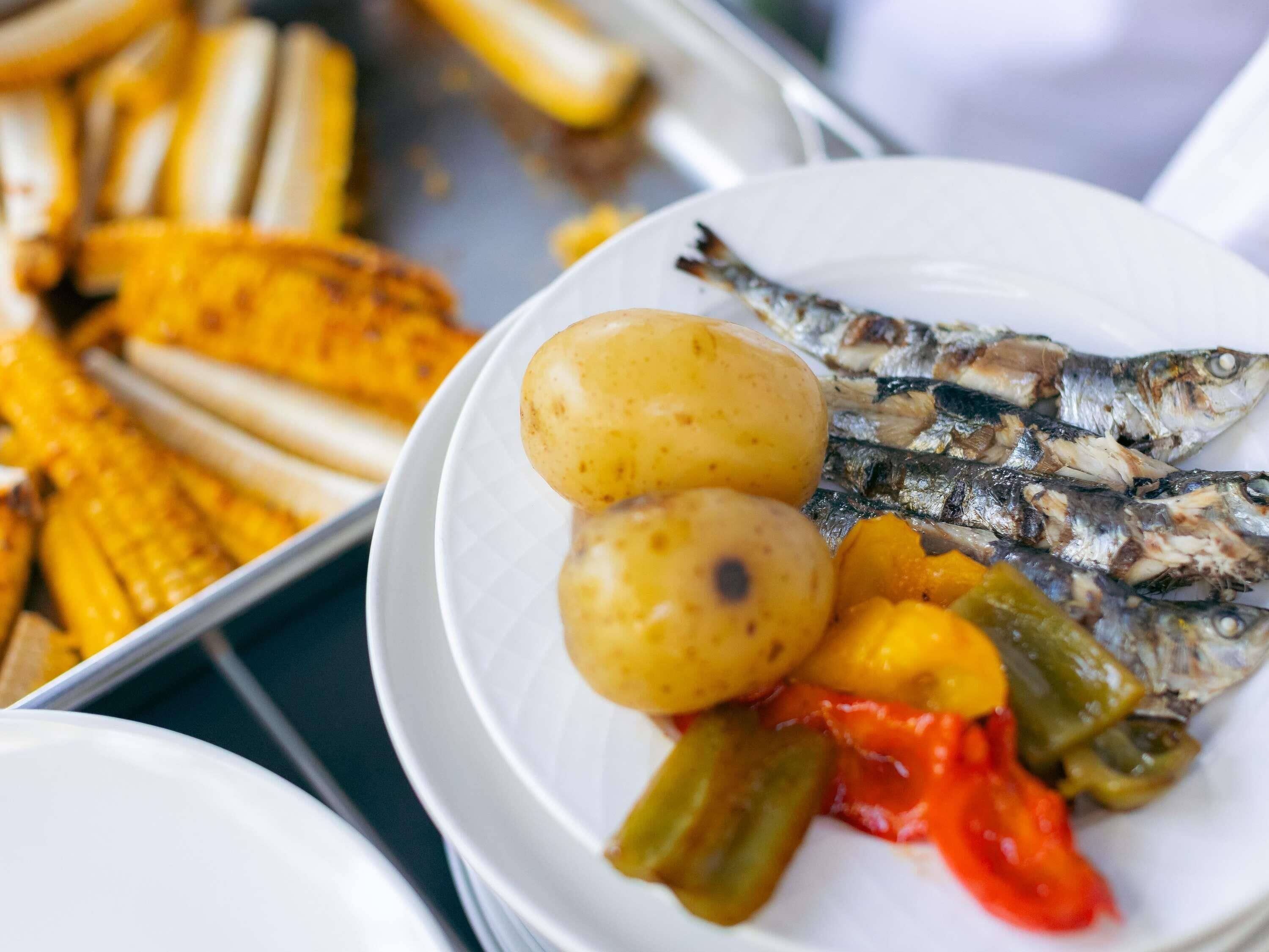 A plate with grilled fish, potatoes, and grilled vegetables.