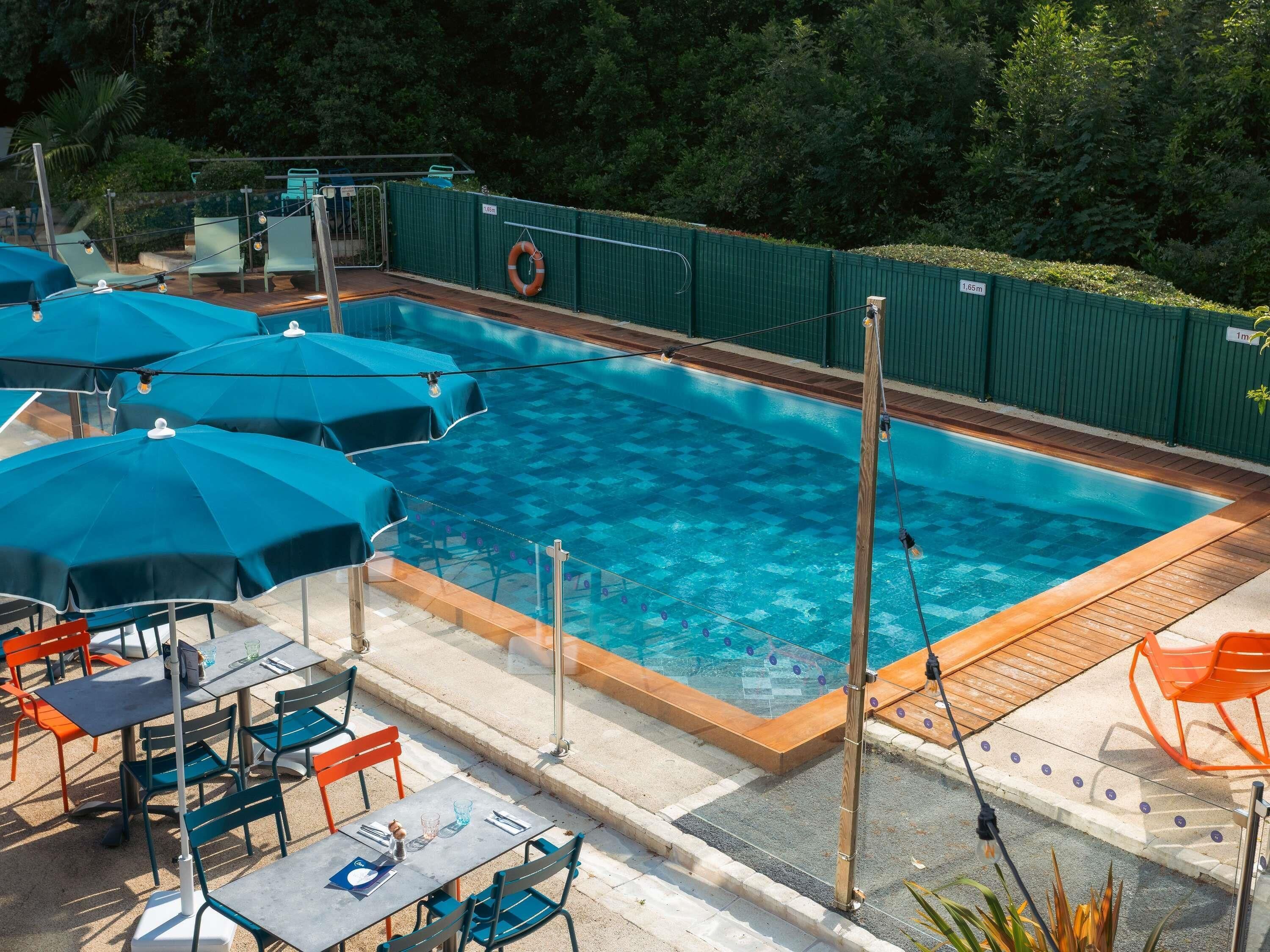Una piscina al aire libre de temporada, sombrillas