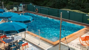 Una piscina al aire libre de temporada, sombrillas