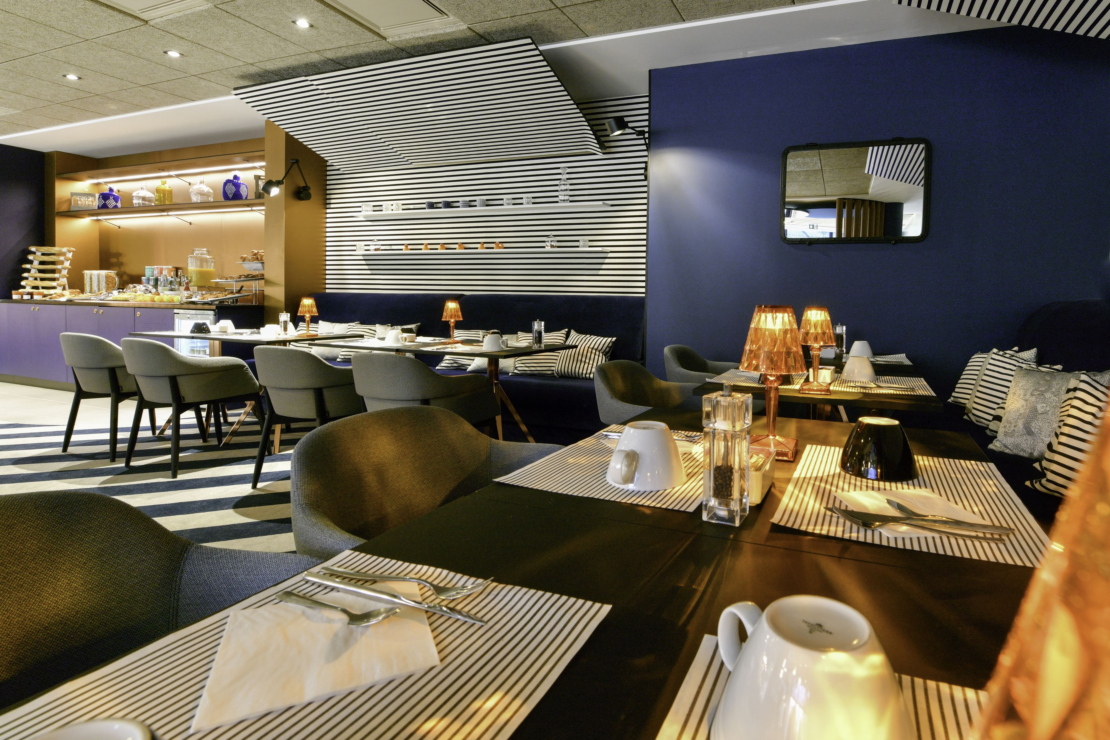 Un restaurante moderno con decoración a rayas, mesas dispuestas y una zona de bar.