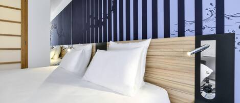 Une chambre d’hôtel avec un grand lit, une tête de lit en bois, un miroir fixé au mur et une table de chevet avec une lampe.