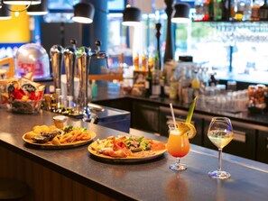A bar area with a variety of food items and drinks, including seafood, pastries, and a cocktail with a straw. - Novotel La Rochelle Centre (La Rochelle)