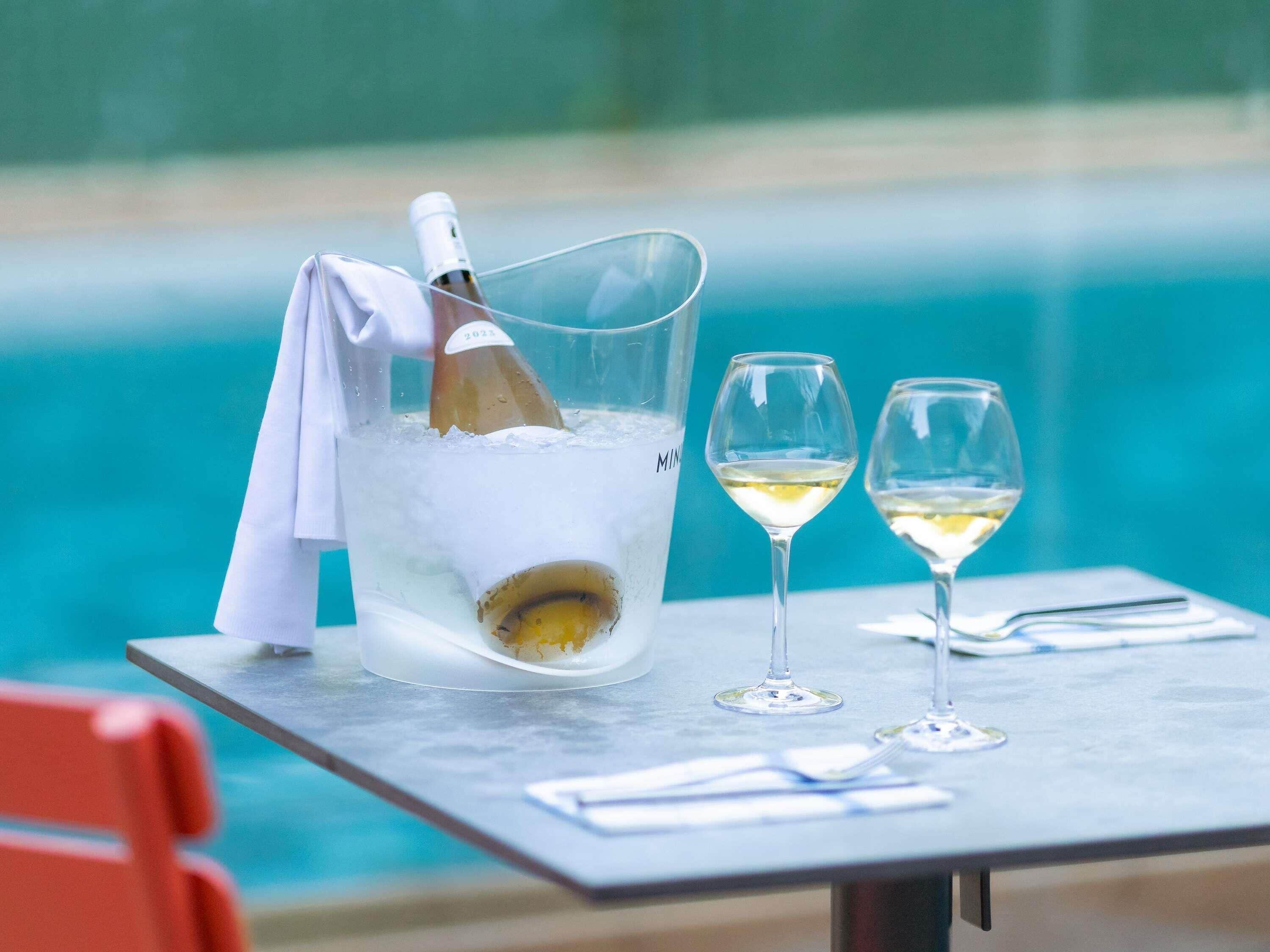 Une table avec un seau à champagne, deux verres de vin blanc et une bouteille de champagne.