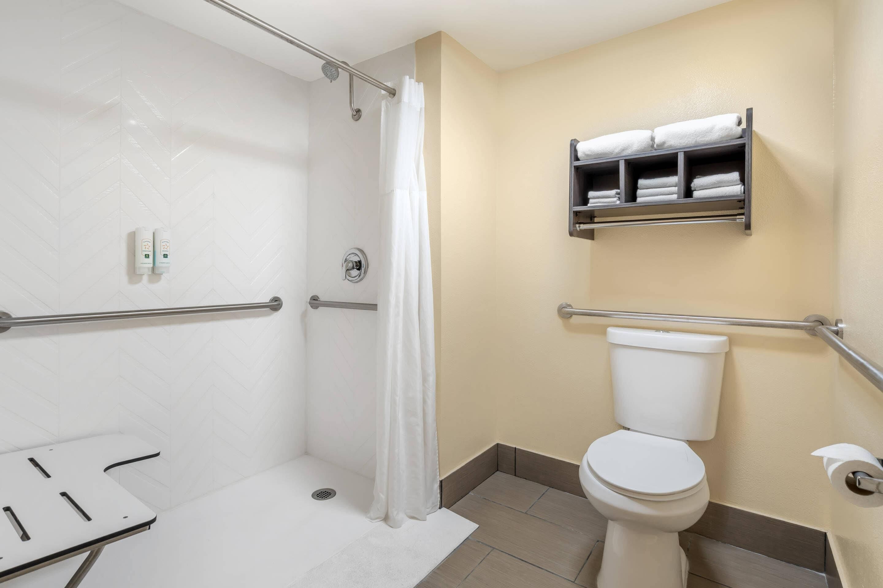 A bathroom with a shower, toilet, and a towel rack.
