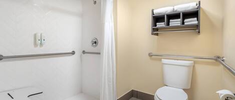 A bathroom with a shower, toilet, and a towel rack.