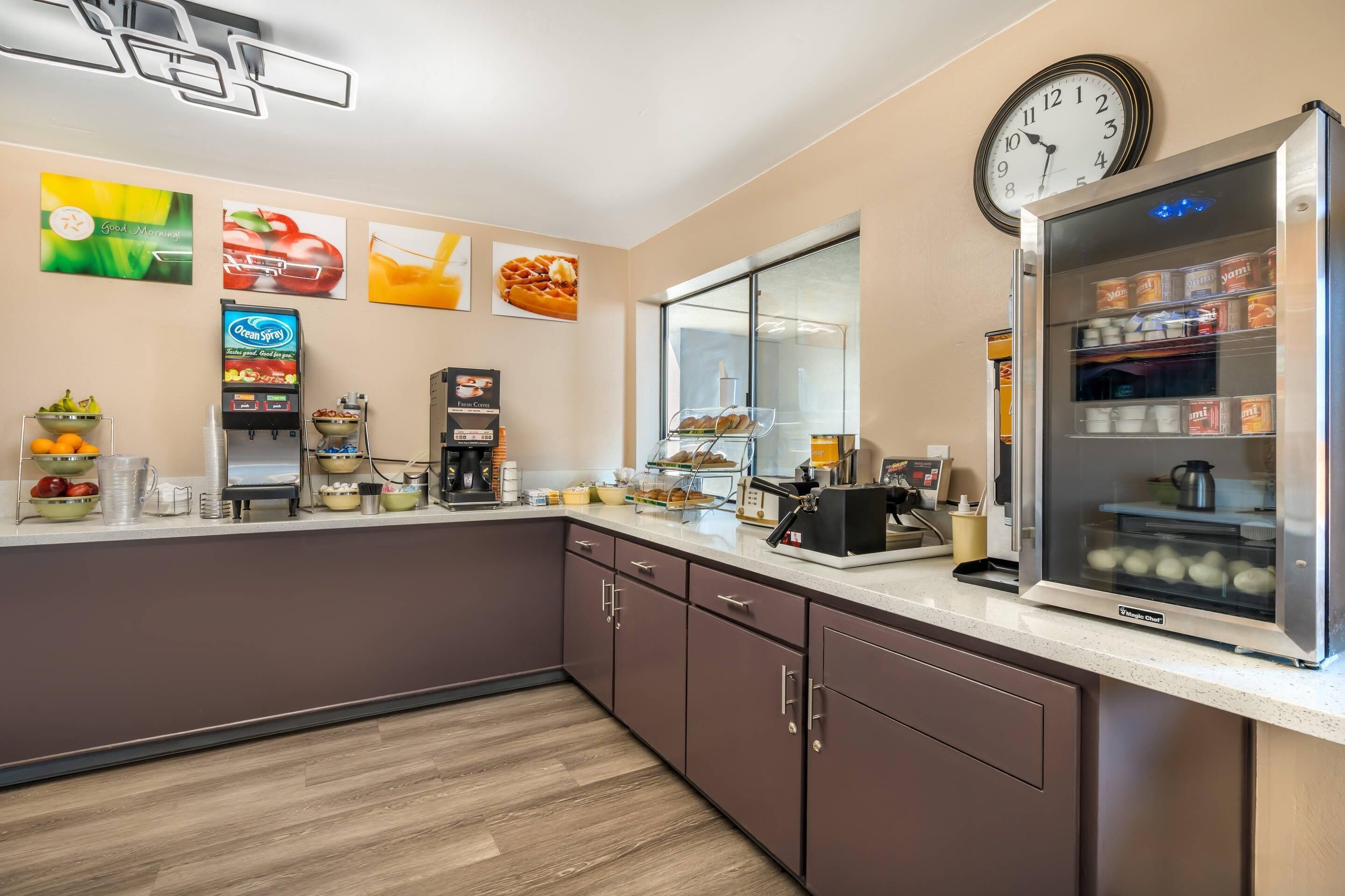 Een moderne keuken met een koelkast, een koffieapparaat en een klok aan de muur.