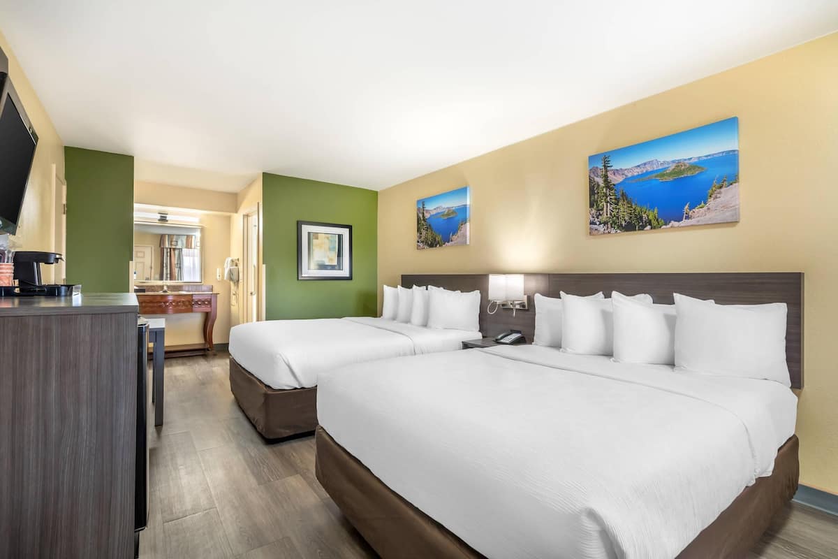 A hotel room with two beds, a desk, and a view of a lake.