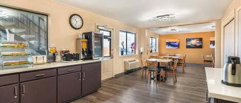 A modern kitchen with a built-in oven, microwave, and coffee maker. There is a dining area with wooden tables and chairs.