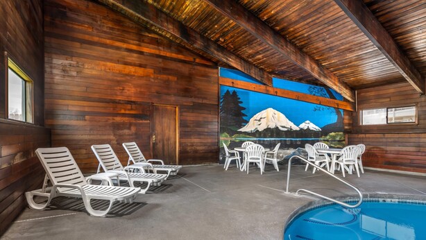 A wooden cabin interior with a pool, lounge chairs, and a mural of a mountain scene. - Quality Inn Klamath Falls - Crater Lake Gateway (Klamath Falls)