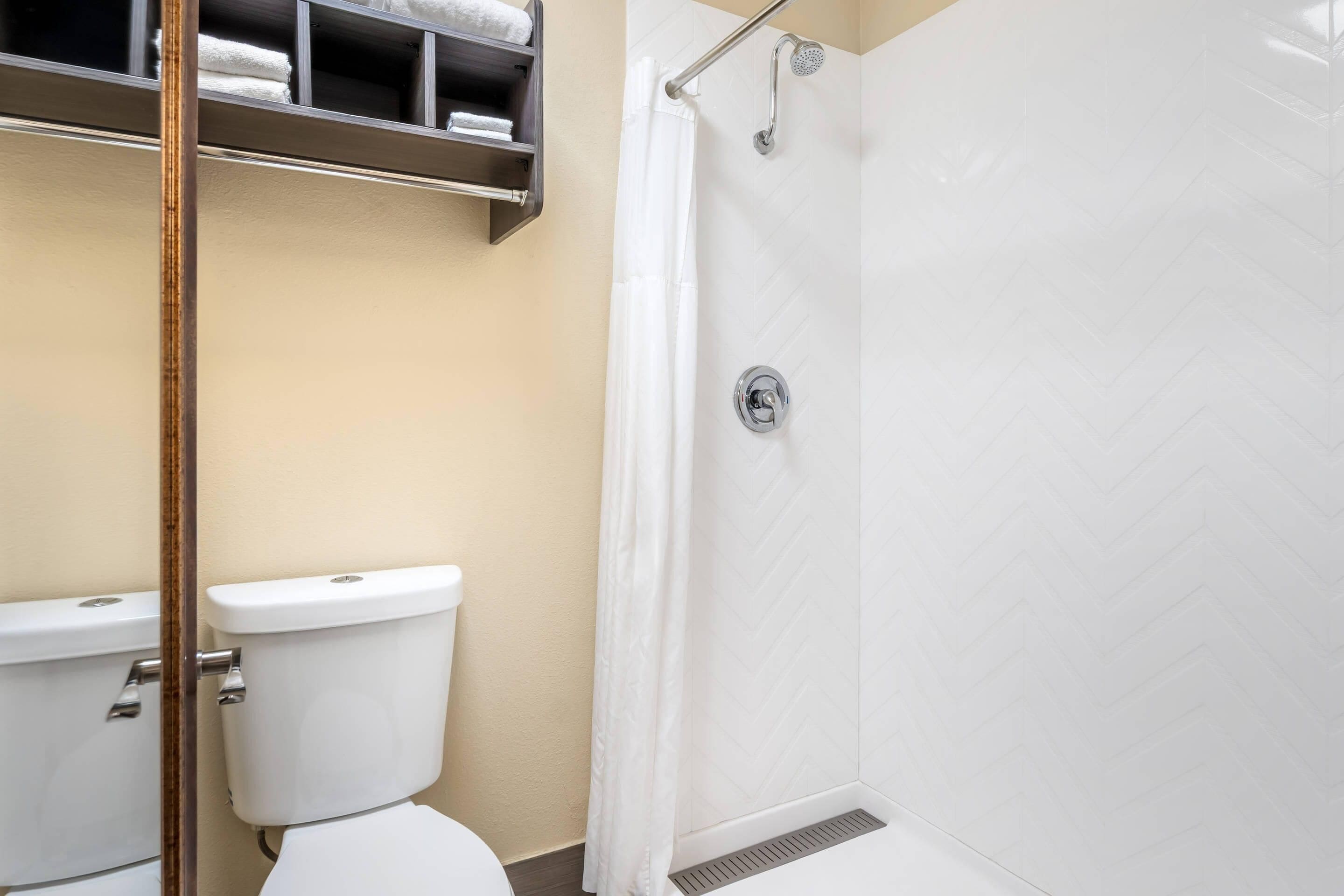 A bathroom with a toilet, a shower with a glass door, and a towel rack with towels.