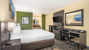 Quarto de hotel com cama, escrivaninha, TV e vista para o mar.
