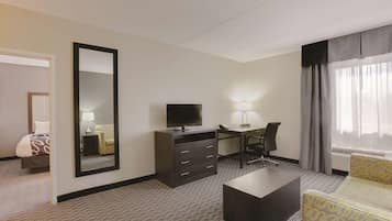 A hotel room with a bed, a desk, a television, a chair, a lamp, and a large mirror.