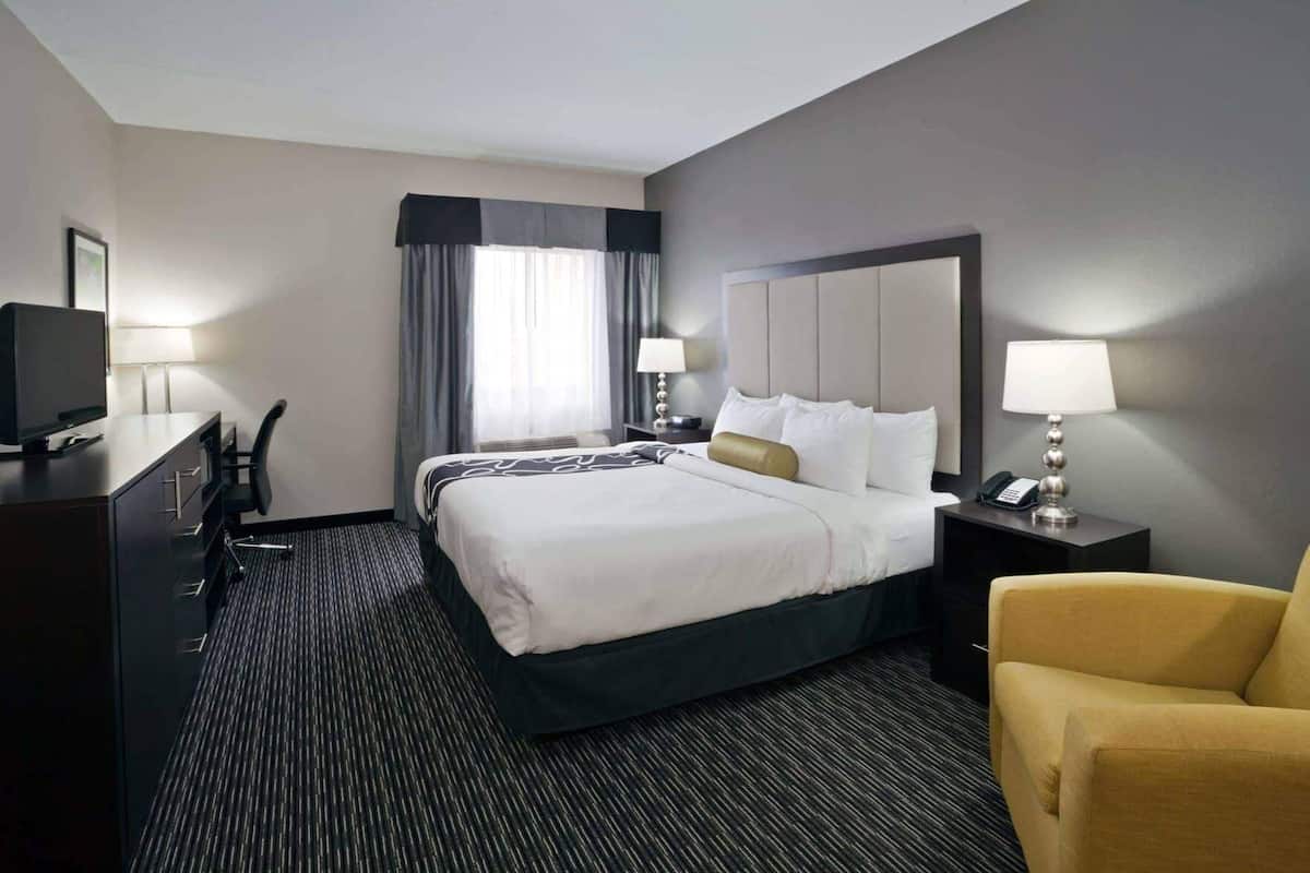 Ein Hotelzimmer mit einem großen Bett, zwei Nachttischlampen, einem Schreibtisch mit Stuhl und einem Sofa.