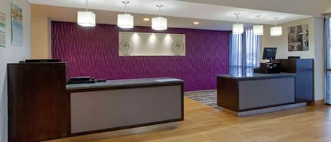 Un área de recepción con dos mostradores, una pared morada y piso de madera.