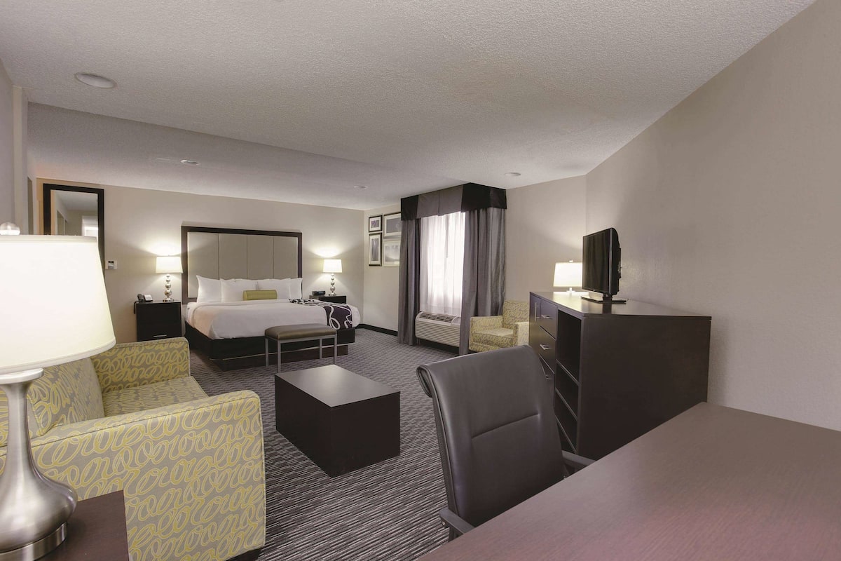 Ein Hotelzimmer mit Bett, Schreibtisch, Stuhl, Sofa, Fernseher und Lampe.