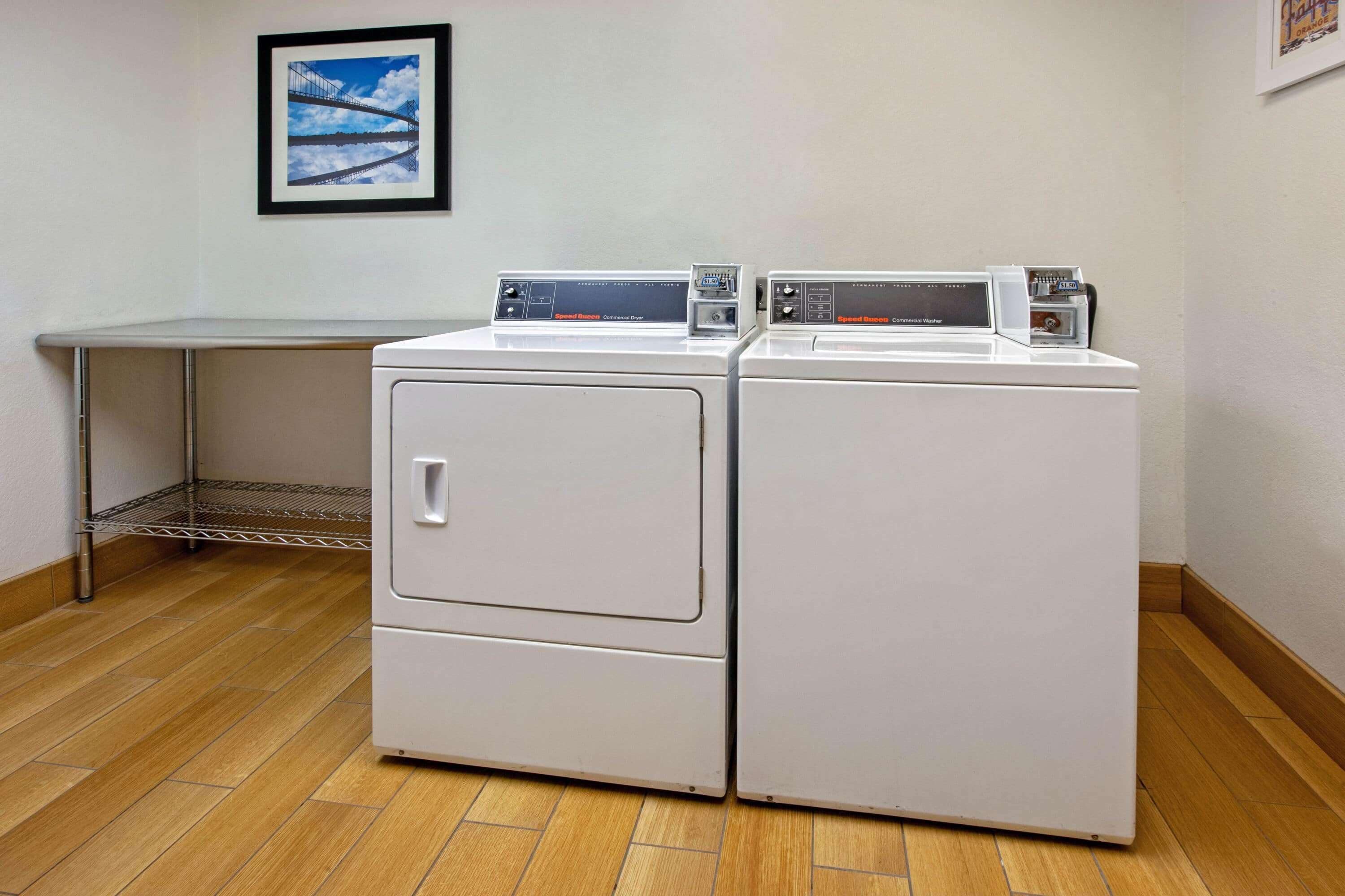 A laundry room with two front-loading washing machines and a metal shelf.